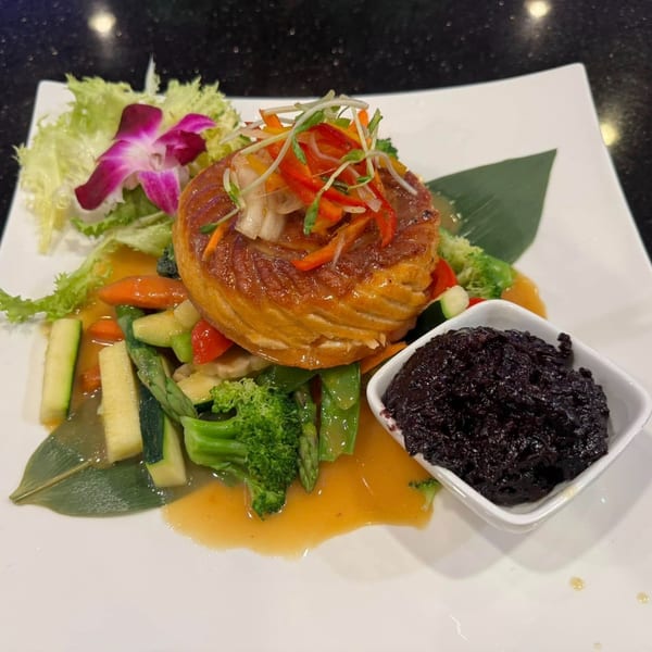 Saga Fusion's Asian-fusion dish with a golden-brown pastry, colorful vegetables, and a side of black rice.