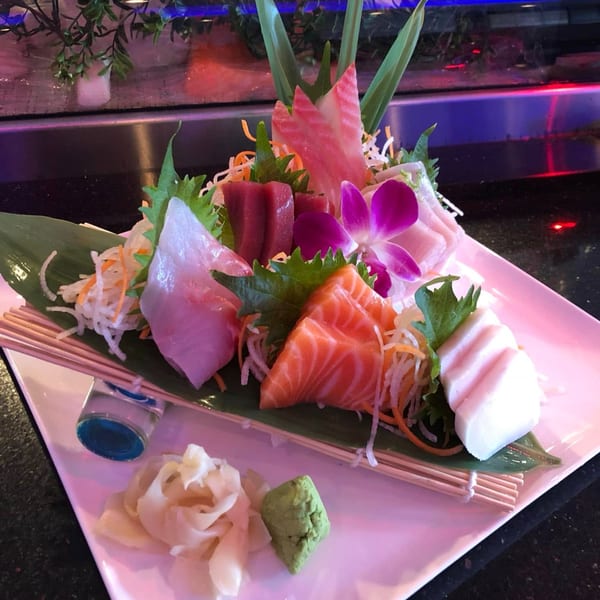 Saga Fusion's sashimi platter with various fish, ginger, wasabi, and an orchid garnish.