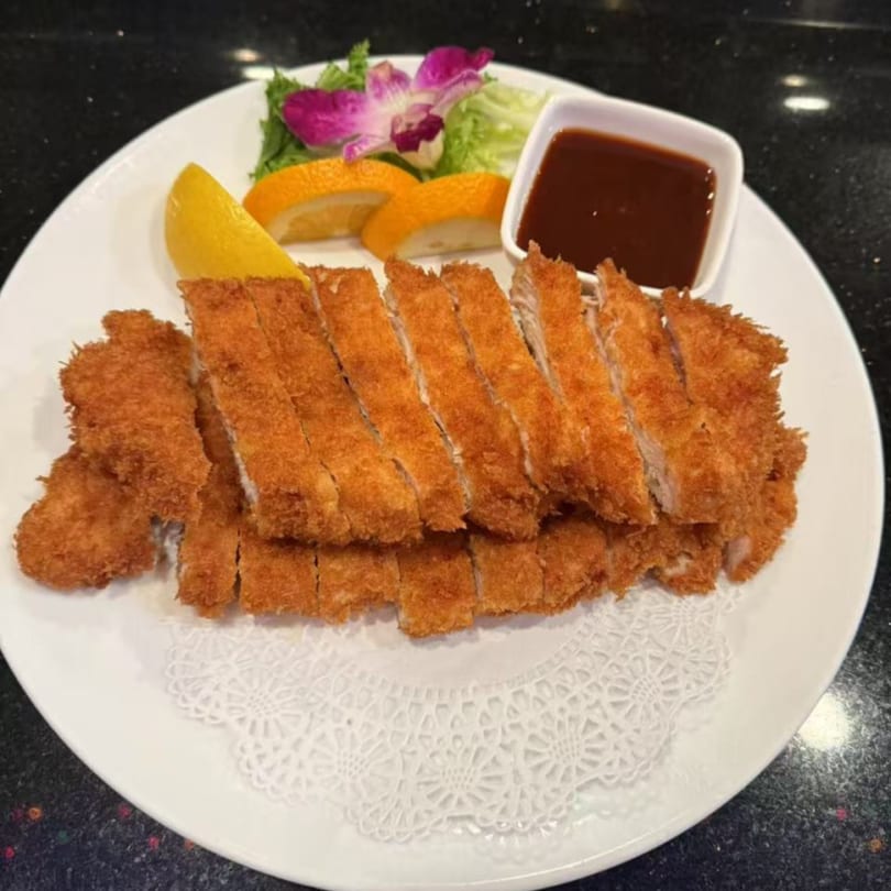 Crispy Saga Fusion chicken katsu, sliced and served with lemon, orange, salad, and dipping sauce.