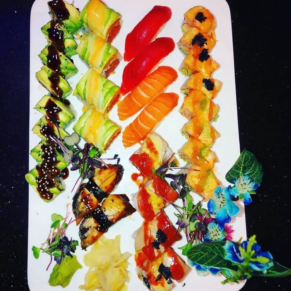 A vibrant platter of Saga Fusion sushi rolls, nigiri, and sashimi, garnished with microgreens and edible flowers.